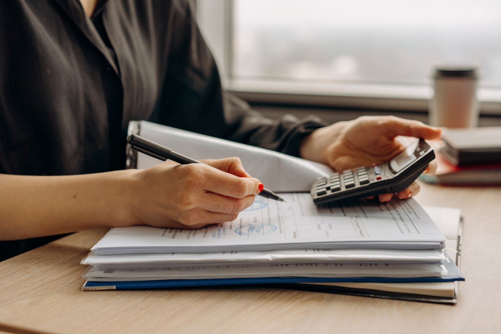 Financial documents, calculator, and coffee on a desk